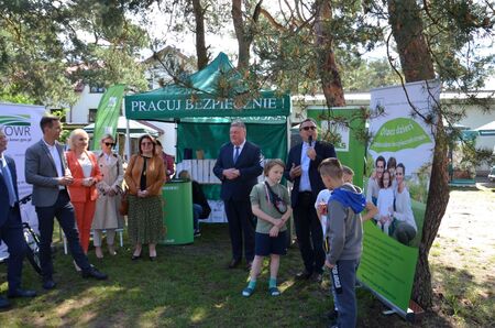 Grupa ludzi przed namiotem w parku (kliknięcie spowoduje powiększenie obrazu)
