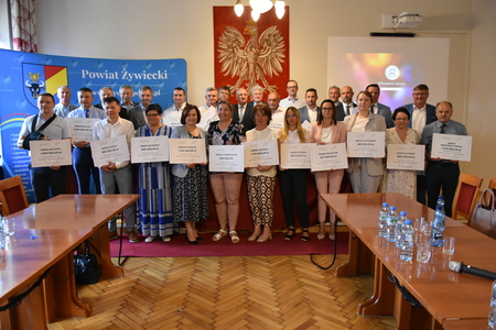 grupa ludzi z tabliczkami dotyczącymi kwoty pozyskanych środków z programu odbudowy zabytków (kliknięcie spowoduje powiększenie obrazu)